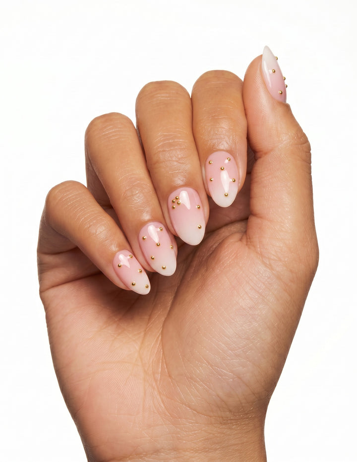 Champagne Dots press-on nails — Almond (extra-short), tan hand, fingers curled