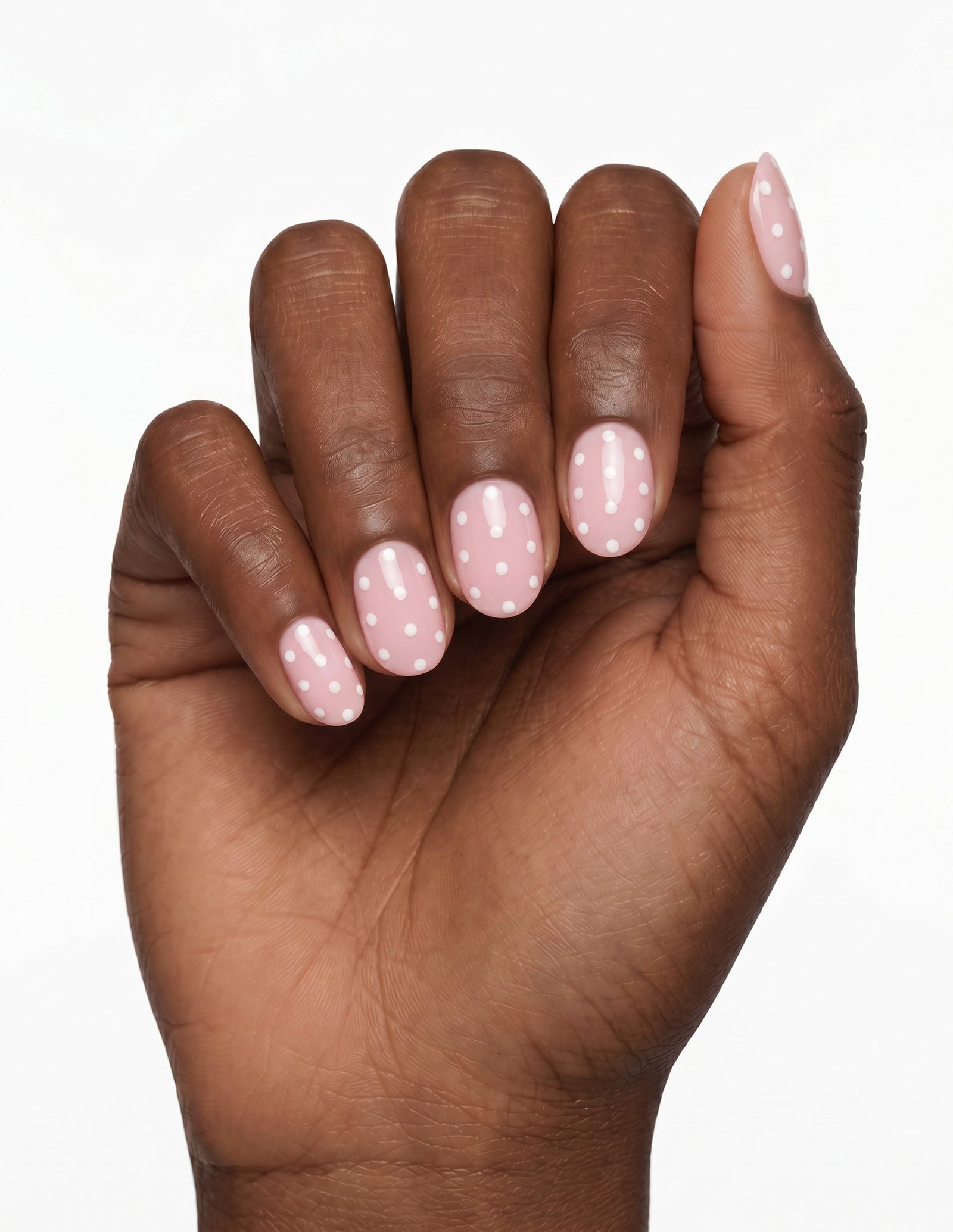 Polka Pink press-on nails — Oval (extra-short), deep-skin hand, fingers curled