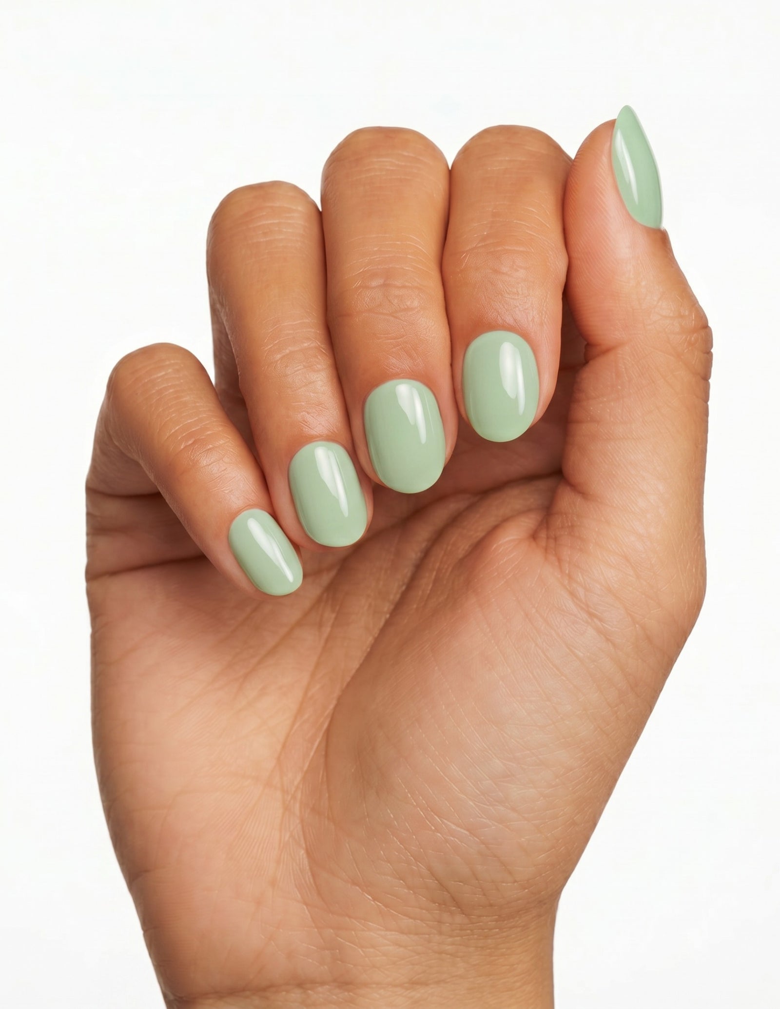Pistachio press-on nails — Oval (extra-short), tan hand, fingers curled