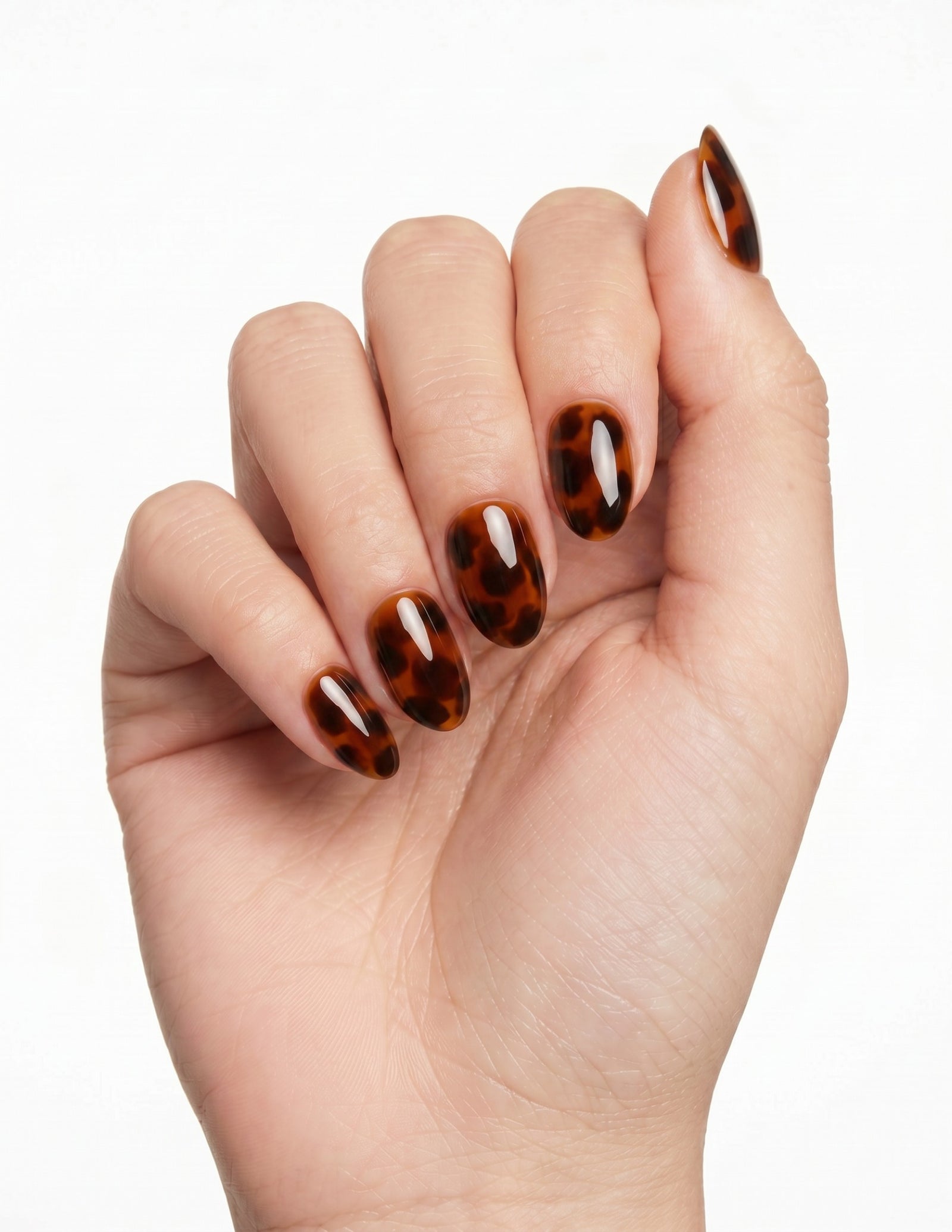 Tortoise press-on nails — Almond (extra-short), light-skin hand, fingers curled