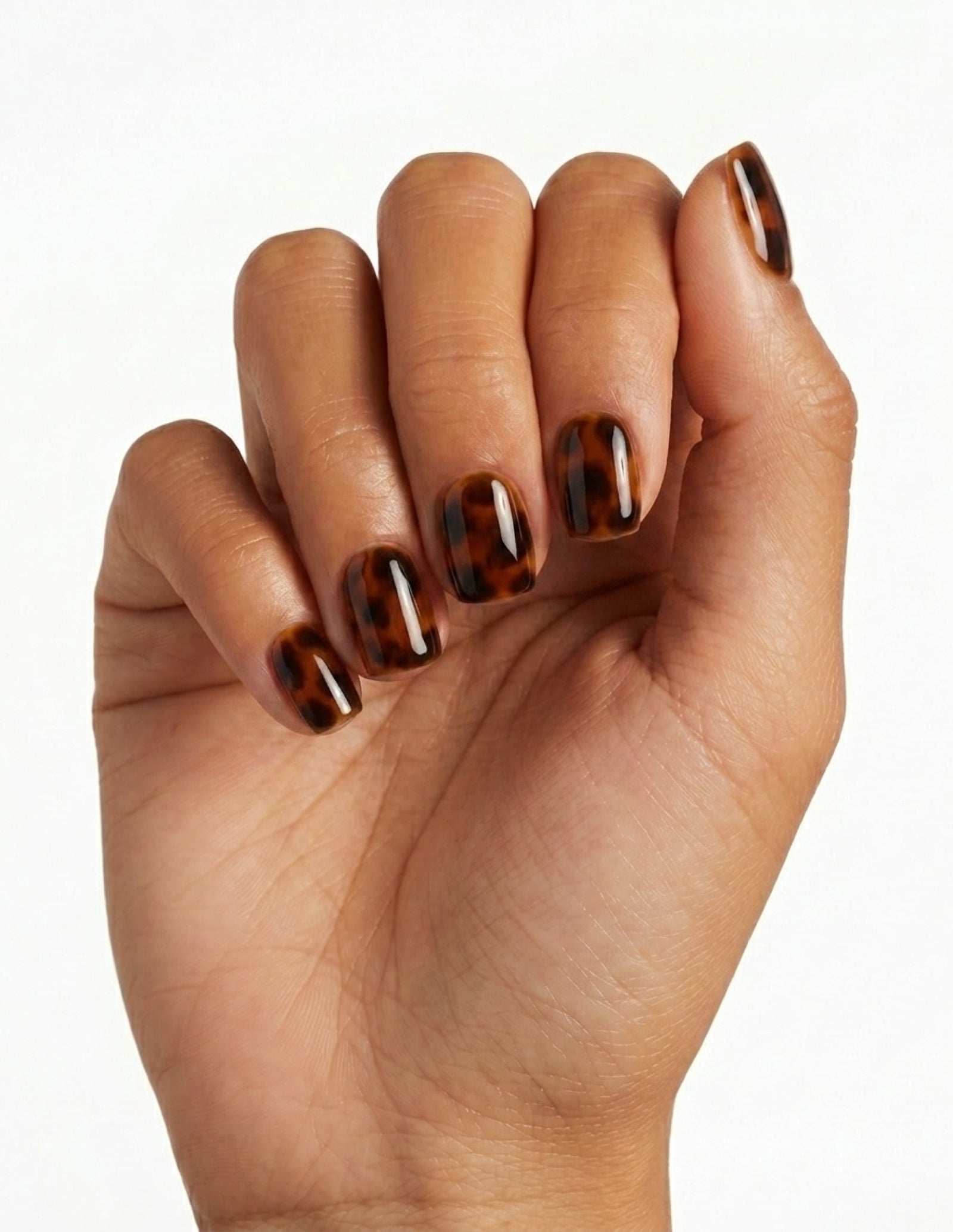 Tortoise press-on nails — Coffin (short), tan hand, fingers curled