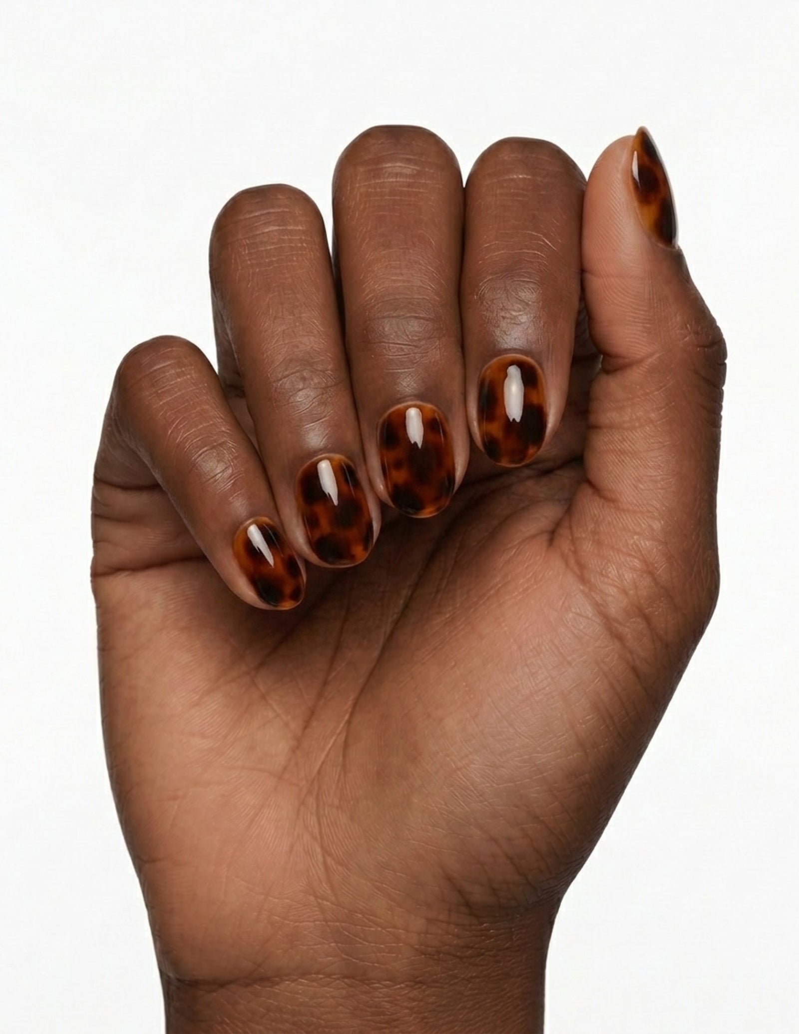 Tortoise press-on nails — Oval (extra-short), deep-skin hand, fingers curled