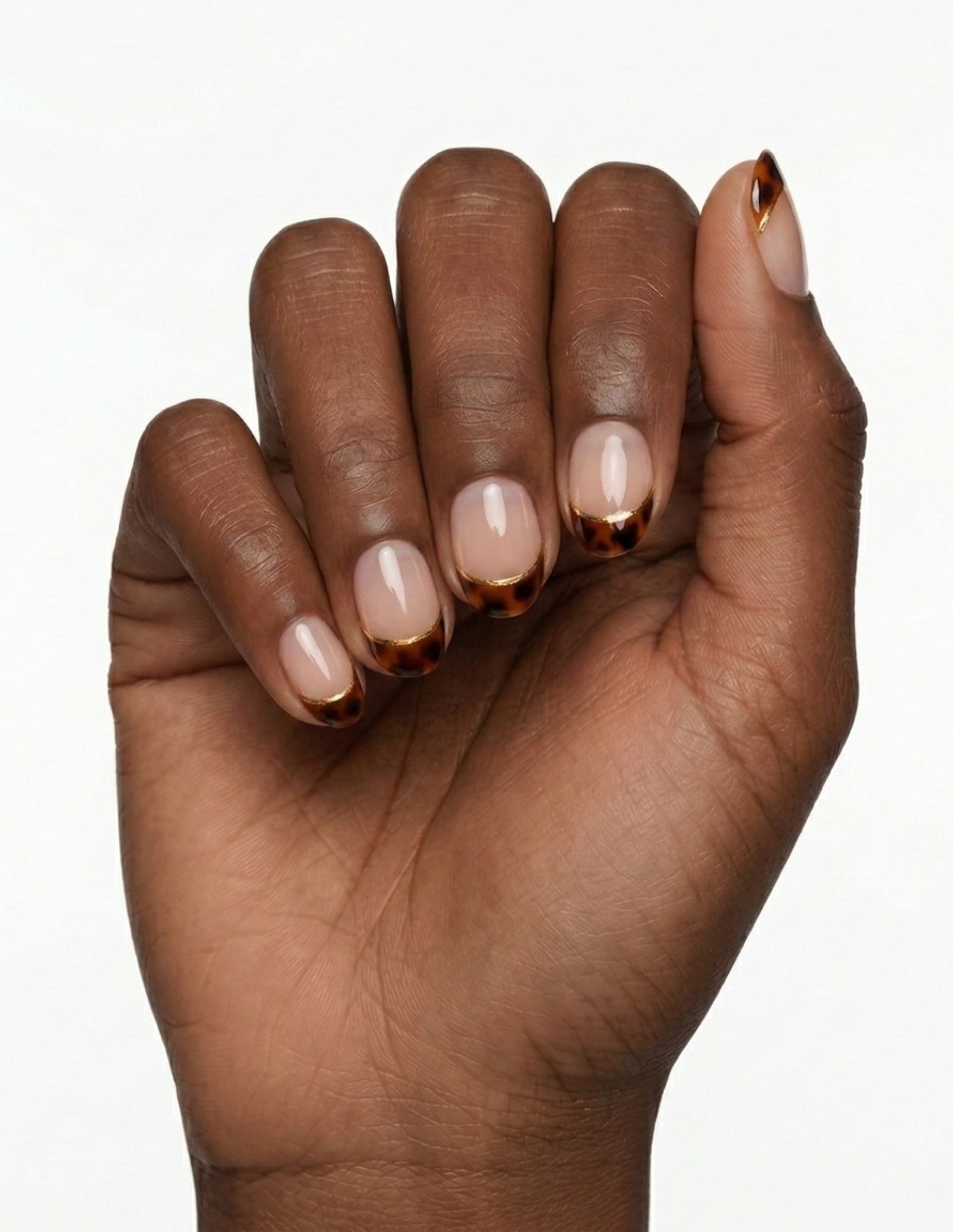 Tortoise Tips press-on nails — Oval (extra-short), deep-skin hand, fingers curled