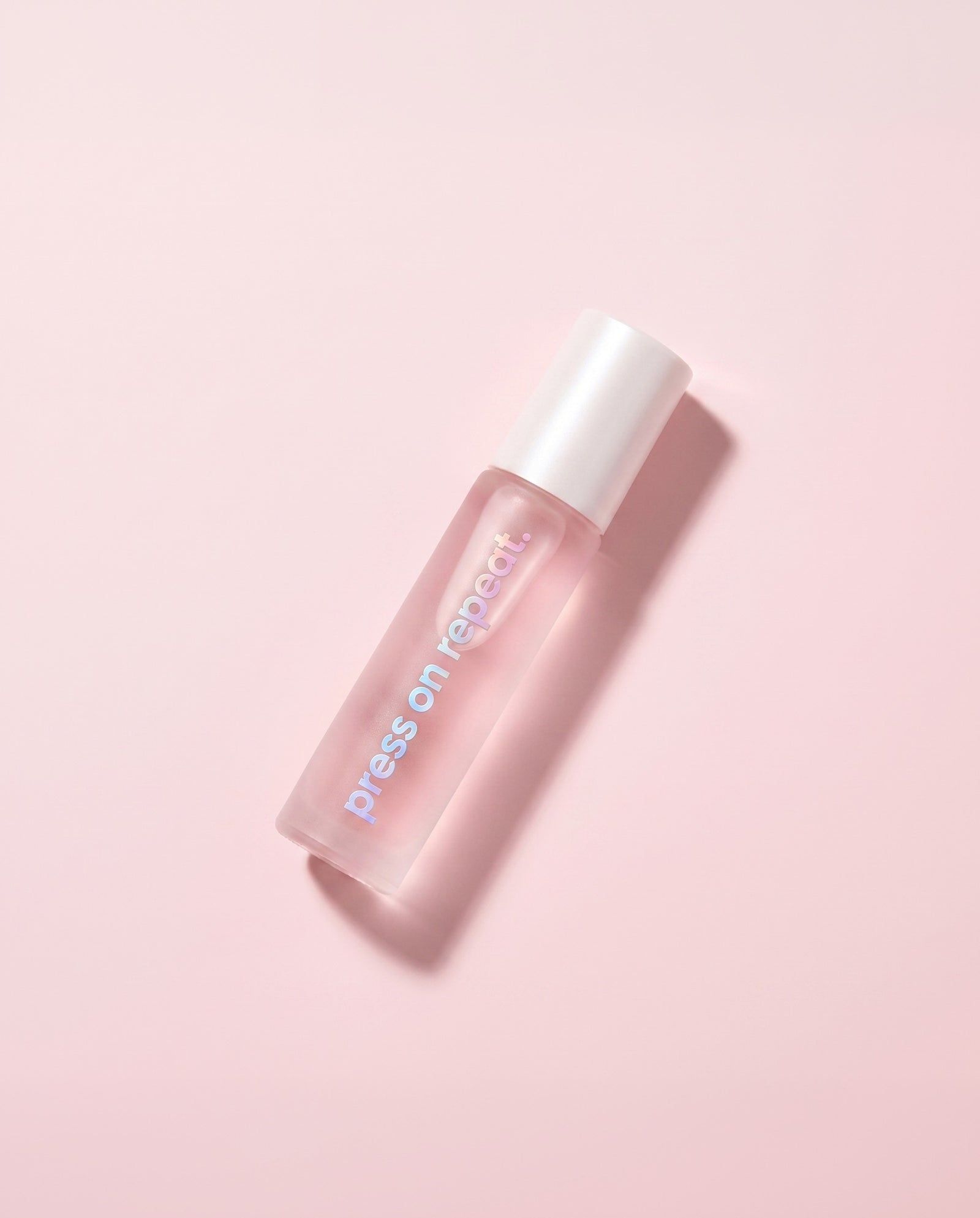 Press On Repeat cuticle oil roll-on lying flat, its vertical wordmark facing the camera.