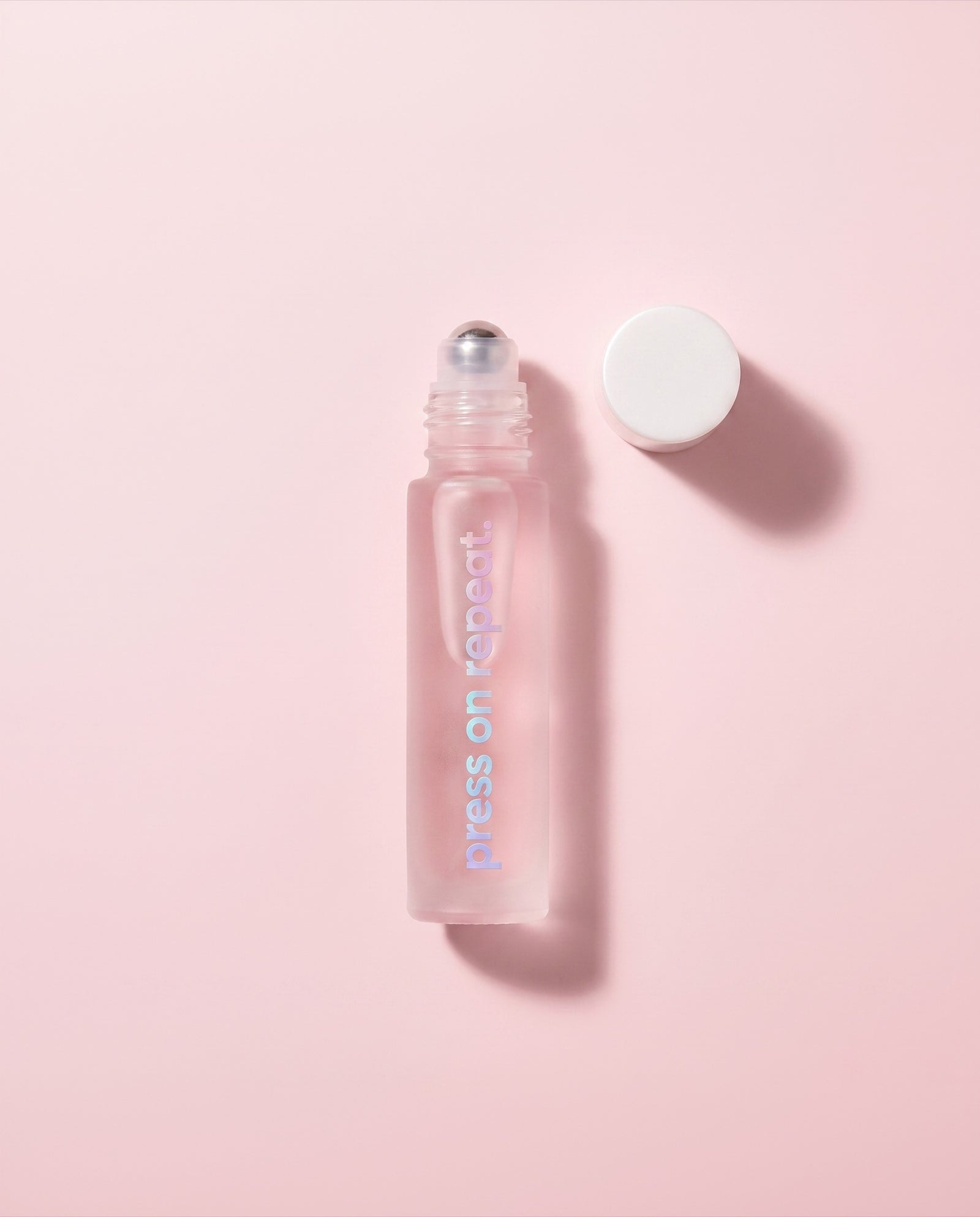 Cuticle oil roll-on with the cap removed beside it, showing the stainless steel rollerball applicator.