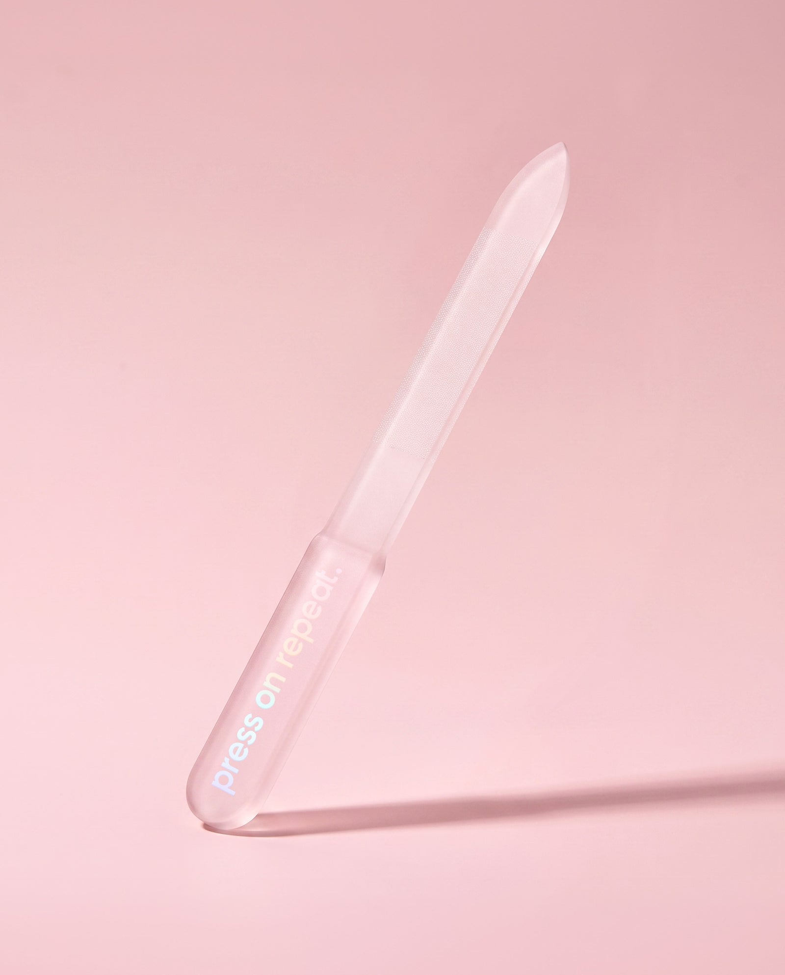 Frosted pink glass nail file standing upright, showing its tapered filing edge.
