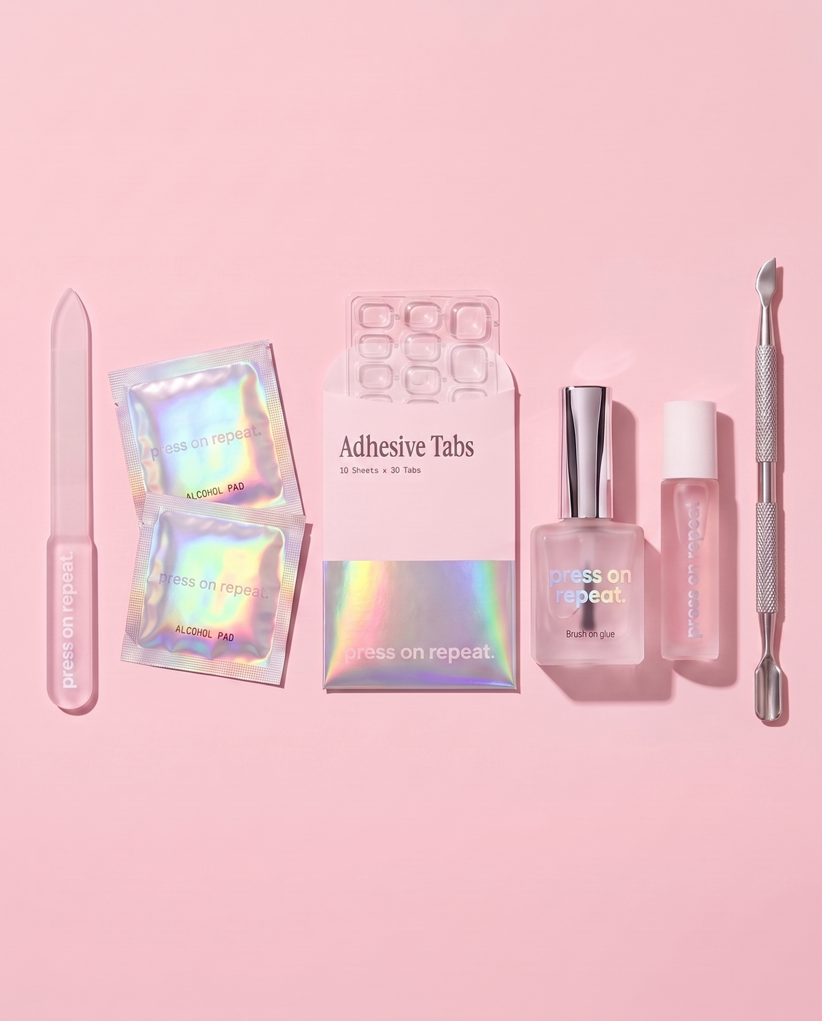 The Nail Kit laid flat: glass nail file, alcohol pads, adhesive tabs, brush-on glue, cuticle oil and a steel cuticle stick.
