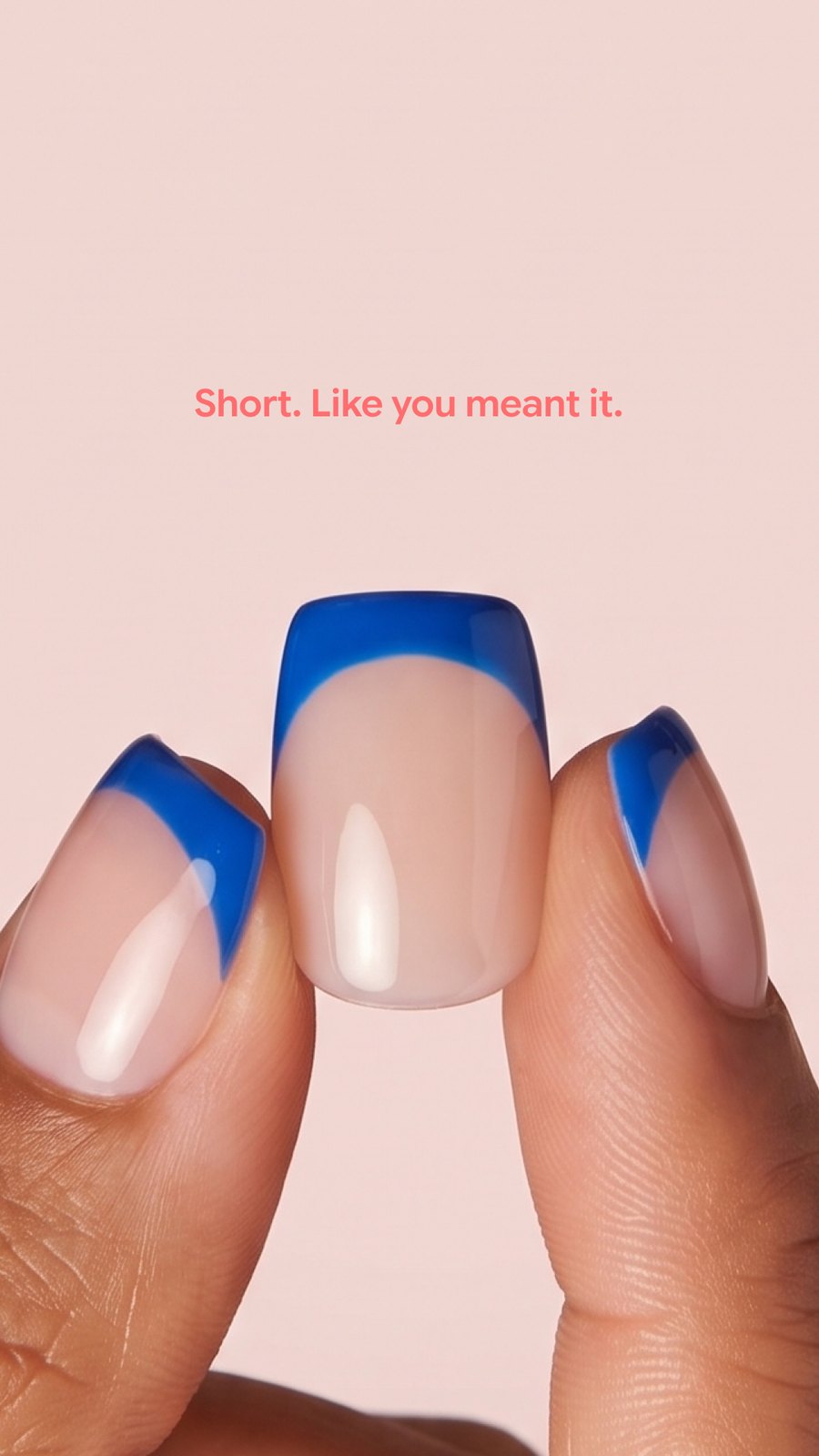 Two fingers wearing extra short press-on nails with a cobalt blue french tip, captioned: short, like you meant it.